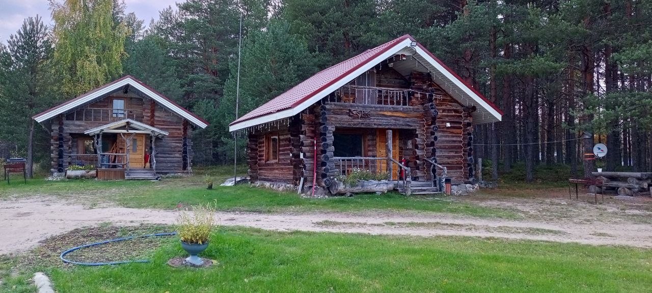 Фасад рубленого дома с деревянным крыльцом и балконом
